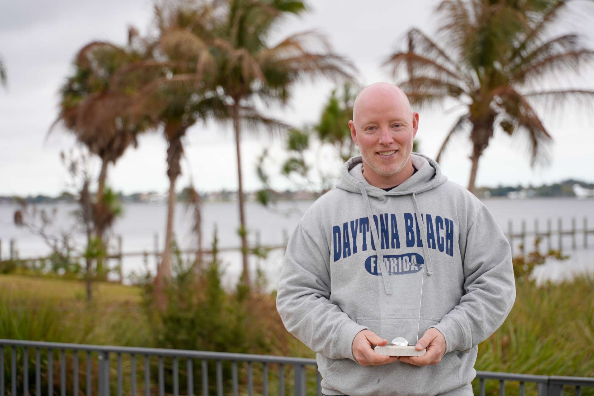 Jeff Benjamin standing in front of water holding his award.